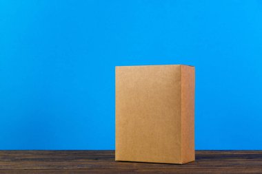 Kopya alanı ile koyu ahşap masa üzerinde sahte için kahverengi karton kutu boş kapandı.