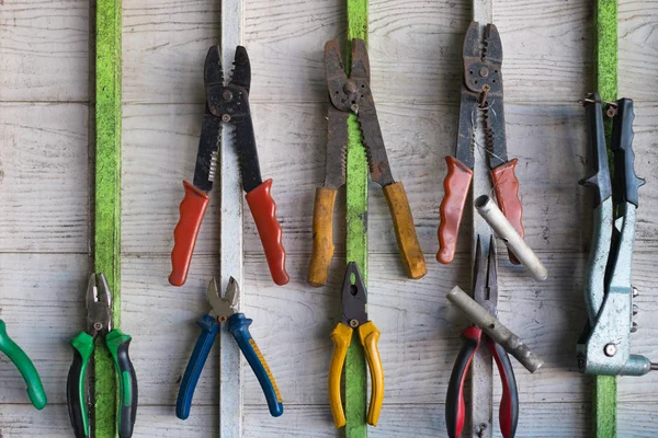 Old hand tools hanging on wall in workshop or auto service garage, many tool shelf against a wall, repair and car mechanic concept.