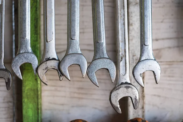 Old hand tools hanging on wall in workshop or auto service garage, many tool shelf against a wall, repair and car mechanic concept.