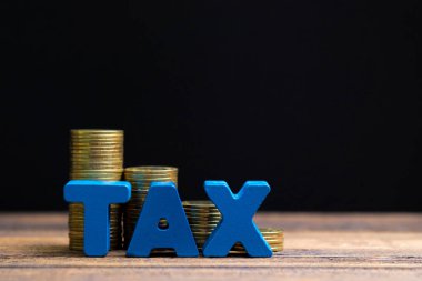 Vergi kavramı. Ahşap çalışma masa koyu arka plan, iş ve finansal kavram fikir para yığını ile vergi alfabesi.