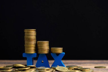 Vergi kavramı. Ahşap çalışma masa koyu arka plan, iş ve finansal kavram fikir para yığını ile vergi alfabesi.