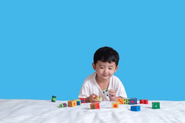 3 yıl eski küçük şirin Asyalı çocuk oynamak oyuncak ya da kare blok bulmaca evde yatakta, yalan blok şekli veya parçalar, eğitim ve sağlıklı kavramı oynayarak öğrenmek.