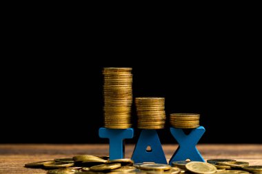 Vergi kavramı. Ahşap çalışma masa koyu arka plan, iş ve finansal kavram fikir para yığını ile vergi alfabesi.