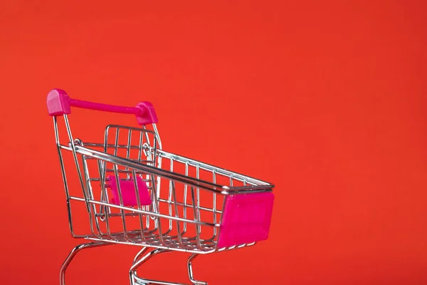赤の背景にカートやスーパー マーケットのトロリーのショッピング ビジネス金融ショッピングのコンセプト アイデア — ストック写真