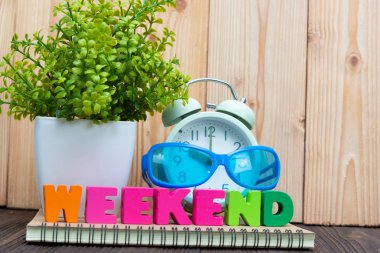 Hafta sonu mektup metin ve defter kağıt, çalar saat ve küçük dekorasyon ağaç ahşap arka plan, Merhaba hafta sonu tatil kavramı fikir üzerinde beyaz cam aranjman.