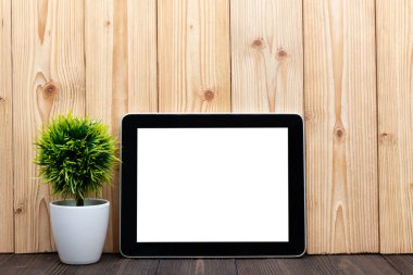 Boş tablet bilgisayar ve küçük ağaç veya çiçek buketi kopya alanı için ahşap zemin üzerine beyaz vazoda metin ekleyin.