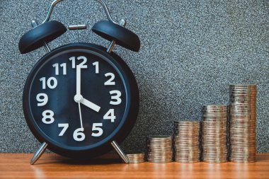 Alarm saati ve para basamaklarının çalışma masasındaki basamakları, tasarruf parası konsepti, bankacılık ve iş fikri zamanı.