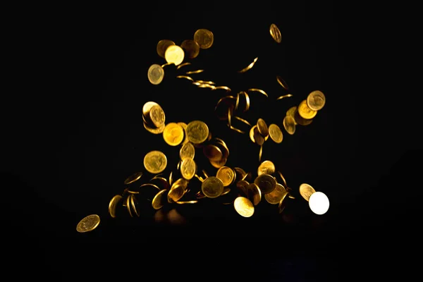 Falling gold coins money in dark background, business concept idea.