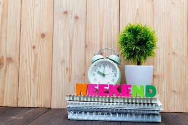 Hafta sonu mektup metin ve defter kağıt, çalar saat ve küçük dekorasyon ağaç ahşap arka plan, Merhaba hafta sonu tatil kavramı fikir üzerinde beyaz cam aranjman.