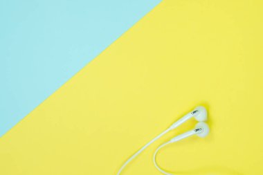 Sohbet tatlı mavi ve sarı renk pastel kağıt, üstten görünüm, doku ve arka plan üzerinde beyaz kulaklık veya kulak buds. müzik dinleme kavram fikir.