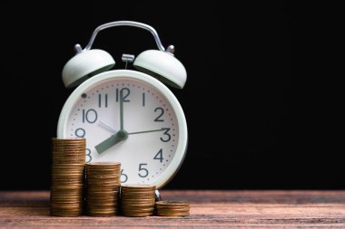 Çalar saat ve karanlık bir odada, tasarruf para kavramı, bankacılık ve iş kavramı fikri çalışma tablo para yığınları.