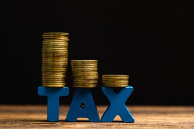 Vergi kavramı. Ahşap çalışma masa koyu arka plan, iş ve finansal kavram fikir para yığını ile vergi alfabesi.