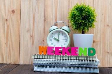 Hafta sonu mektup metin ve defter kağıt, çalar saat ve küçük dekorasyon ağaç ahşap arka plan, Merhaba hafta sonu tatil kavramı fikir üzerinde beyaz cam aranjman.