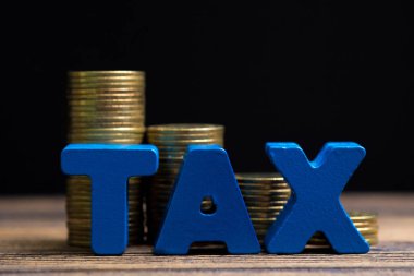 Vergi kavramı. Ahşap çalışma masa koyu arka plan, iş ve finansal kavram fikir para yığını ile vergi alfabesi.