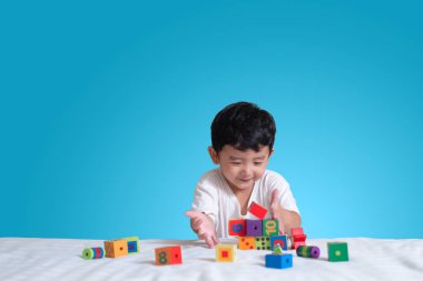 3 yıl eski küçük şirin Asyalı çocuk oynamak oyuncak ya da kare blok bulmaca evde yatakta, yalan blok şekli veya parçalar, eğitim ve sağlıklı kavramı oynayarak öğrenmek.