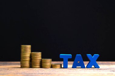 Vergi kavramı. Ahşap çalışma masa koyu arka plan, iş ve finansal kavram fikir para yığını ile vergi alfabesi.