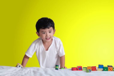 3 yıl eski küçük şirin Asyalı çocuk oynamak oyuncak ya da kare blok bulmaca evde yatakta, yalan blok şekli veya parçalar, eğitim ve sağlıklı kavramı oynayarak öğrenmek.