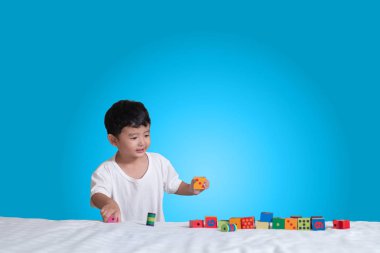 3 yıl eski küçük şirin Asyalı çocuk oynamak oyuncak ya da kare blok bulmaca evde yatakta, yalan blok şekli veya parçalar, eğitim ve sağlıklı kavramı oynayarak öğrenmek.