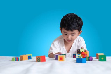 3 yıl eski küçük şirin Asyalı çocuk oynamak oyuncak ya da kare blok bulmaca evde yatakta, yalan blok şekli veya parçalar, eğitim ve sağlıklı kavramı oynayarak öğrenmek.