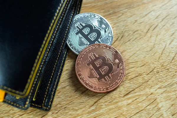 Bitcoin digital currency instead real money, bit-coin with leather wallet or purse on wooden working table, virtual cryptocurrency money business concept idea.