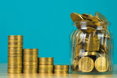 Madeni para yığınları ve altın sikke para cam kavanoz tablo kaydetme gelecekteki bankacılık finans için yeşil arka plana sahip konsept fikir.