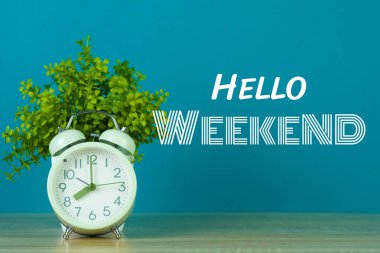 Hafta sonu metin yeşil arka plan ve beyaz vazo içinde küçük ağaç ahşap masa vintage çalar saat ile Merhaba.