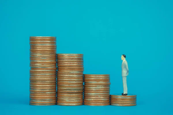 Figure miniature businessman or small people investor and office worker secretary standing on coin stack, for money and financial business success concept idea.
