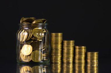 Madeni para yığınları ve altın sikke para cam kavanoz gelecekteki bankacılık finans için kaydetme için koyu arka plan üzerinde kavram fikir.