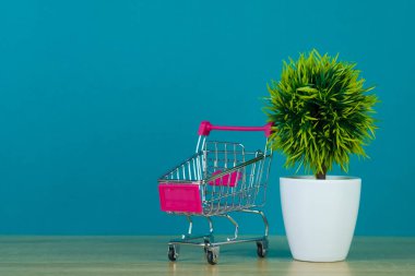 Küçük dekorasyon ağaç ile sepeti ya da süpermarket arabası alışveriş ve konsept pazarlama İşletme Finansı için kopya alanı ile ahşap masa üzerinde alışveriş.