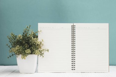 Kopya alanı için Beyaz ahşap masa açık yeşil duvar zemin üzerine boş defter eklemek metin veya reklam word, menü mockup.