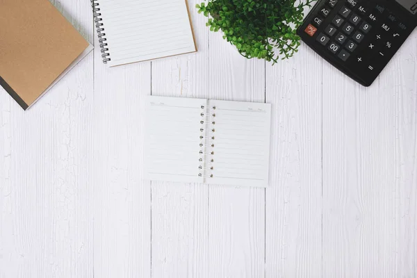 Fountain pen or ink pen with notebook paper and calculator on wooden working table with copy space, office desk concept idea. top view.