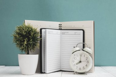 Ofis, banka donatımı veya office temel araçları öğelerini çalışma alanı, defter, çalar saat ve yeşil duvar arka plan kopya alanı ile küçük ağaç ahşap masa