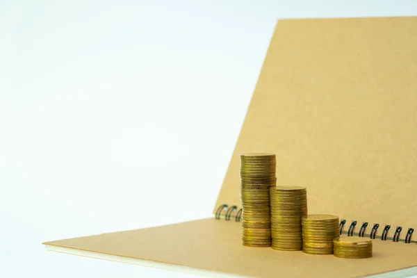 Step of coins stack on notebook paper with copy space for add text, financial and business planning concept idea.