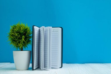 Kopya alanı için Beyaz ahşap masa açık mavi duvar zemin üzerine boş defter eklemek metin veya reklam word, menü mockup.