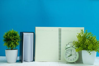 Ofis, banka donatımı veya office temel araçları öğelerini çalışma alanı, defter, çalar saat ve mavi duvar arka plan kopya alanı ile küçük ağaç ahşap masa