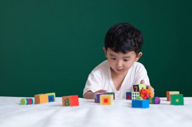 3 yaşında Asyalı çocuk oyun oyuncak ya da kare blok bulmaca yeşil kara tahta ya da okul yönetimi arka plan üzerinde çocuk yalan blok şekli veya parçalar, eğitim kavramı fikir oynayarak öğrenir.