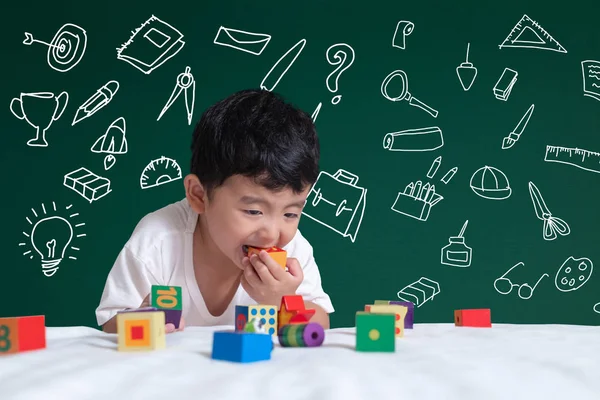 Asian kid learning by playing with his imagination about stationery supplies school object activities for learning, hand drawn on the green chalkboard, education back to school concept idea.