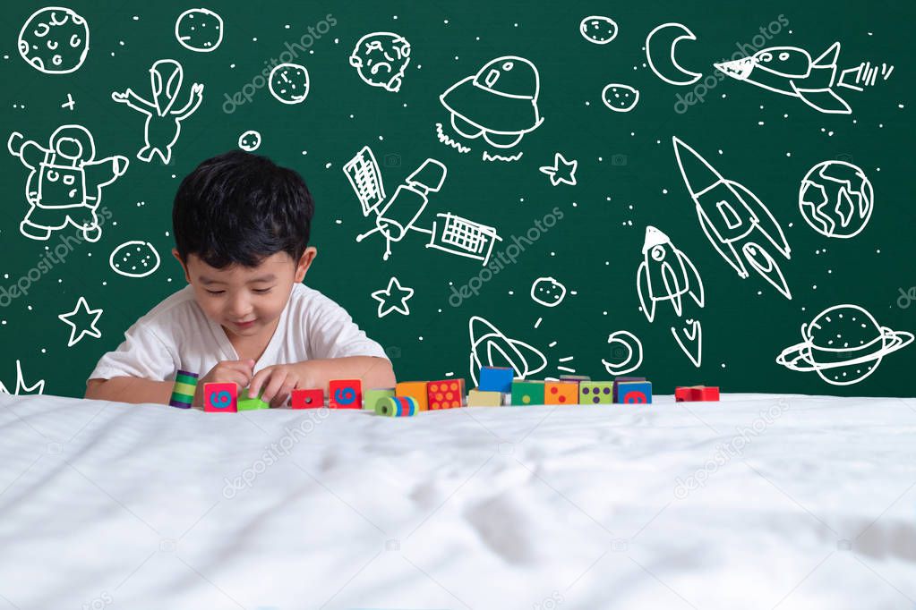 Asian kid learning by playing with his imagination about science and space adventure, hand drawn on the green chalkboard, education back to school and discovery concept idea.