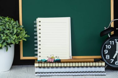 Geri okul ve eğitim kavramı bir fikir, yeşil kara tahta için defter kağıt, ileti örneği veya okul malzemeleri yığını ile.