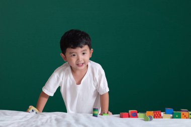 3 yaşında Asyalı çocuk oyun oyuncak ya da kare blok bulmaca yeşil kara tahta ya da okul yönetimi arka plan üzerinde çocuk yalan blok şekli veya parçalar, eğitim kavramı fikir oynayarak öğrenir.