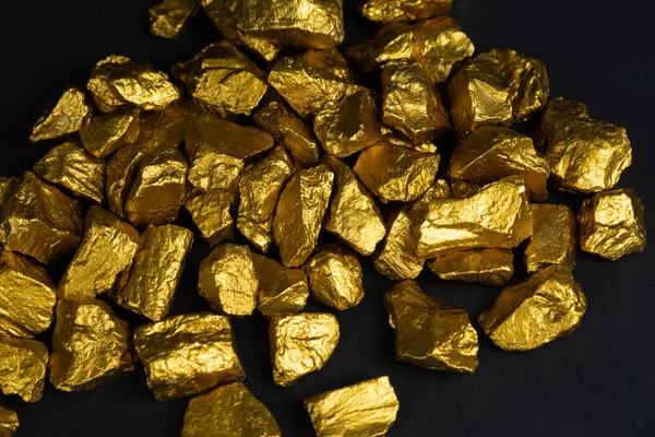 A pile of gold nuggets or gold ore on black background, precious stone or lump of golden stone, financial and business concept idea.