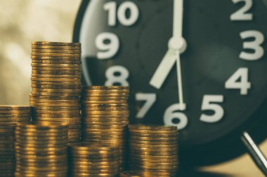 Çalar saat ve çalışma tablosu, tasarruf para kavramı, bankacılık ve iş kavramı fikri üzerinde para yığınları.