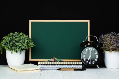 Geri okul ve eğitim kavramı bir fikir, yeşil kara tahta için defter kağıt, ileti örneği veya okul malzemeleri yığını ile.