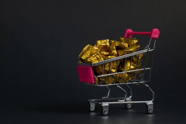 Altın nuggets veya alışveriş sepeti ya da süpermarket arabası siyah arka plan, kıymetli taş veya yumru altın taş, mali ve iş kavramı fikri altın cevheri yığını.