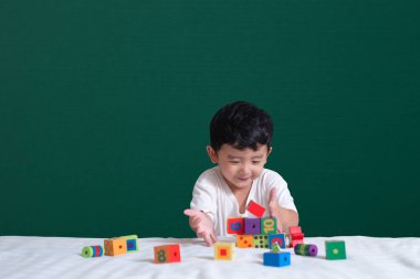 3 yaşında Asyalı çocuk oyun oyuncak ya da kare blok bulmaca yeşil kara tahta ya da okul yönetimi arka plan üzerinde çocuk yalan blok şekli veya parçalar, eğitim kavramı fikir oynayarak öğrenir.