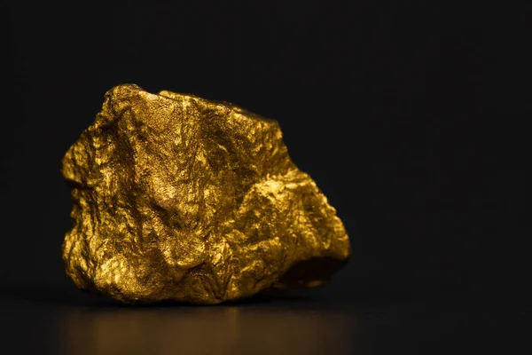Closeup of gold nugget or gold ore on black background, precious stone or lump of golden stone, financial and business concept idea.