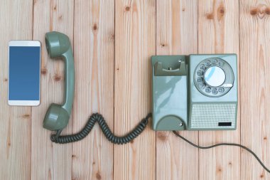Retro döner telefon veya vintage telefon kablosu ve yeni cep telefonu ile veya ahşap masa, kopya alanı ile üstten görünüm, teknoloji ilerleme kavramı akıllı telefon.
