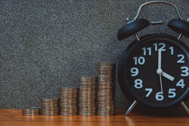 Alarm saati ve para basamaklarının çalışma masasındaki basamakları, tasarruf parası konsepti, bankacılık ve iş fikri zamanı.
