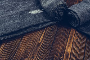 Frayed kot pantolon ya da kot denim koleksiyonu kaba koyu ahşap masa arka plan kopya alanı, eski moda stil kavramı ile rulo.