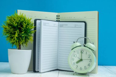 Ofis, banka donatımı veya office temel araçları öğelerini çalışma alanı, defter, çalar saat ve mavi duvar arka plan kopya alanı ile küçük ağaç ahşap masa